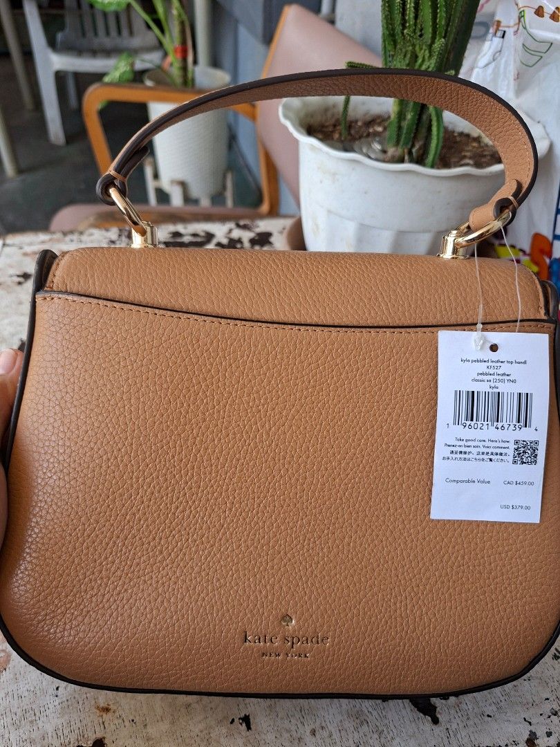 Kate Spade Kyla Pebbled Leather Top Handle Bag (Category: Tote Bags) located in Imus. Submitted by graceannes06899 (Listing ID 1466194908, Image 2). Description: - Brand: Kate Spade - Style: Kyla Top Handle Bag - Color: Classic Camel - Material: Premium pebble leather - Hardware: Gold-tone with logo lettering - Closure: Secure zip top with fabric lining - Extras: Includes structured top handle and adjustable strap - Condition: Brand new with orig