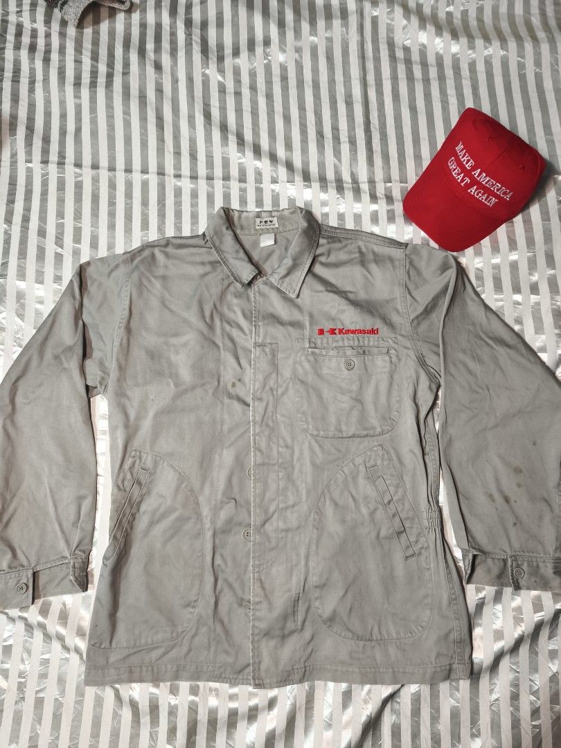 Kawasaki Vintage Grey Workwear Jacket (Category: Coats, Jackets and Outerwear) located in Baguio. Submitted by boneteezandharmony (Listing ID 1466330349, Image 1). Description: - Color: Grey - Details: Red Kawasaki embroidery on chest pocket, button-up front, collar, and large front pockets - Origin: Japanese tagging inside the collar - Condition: Light spotting and stains on front and sleeves - Style: Rugged mechanic / utility wear.