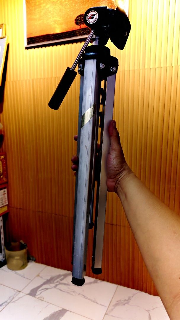 Kenko ST-60 Camera Tripod (Category: Tripods & Monopods) located in Bulacan. Submitted by babz30261 (Listing ID 1466166631, Image 1). Description: - Brand/Model: Kenko ST-60 Tripod - Build: Sturdy silver aluminum - Height Adjustment: Easy central crank handle - Head: Includes smooth pan head with control handle - Legs: Three-section with secure plastic flip locks - Condition: Fully functional; shows minor scuffs and dust from previous use - Best 