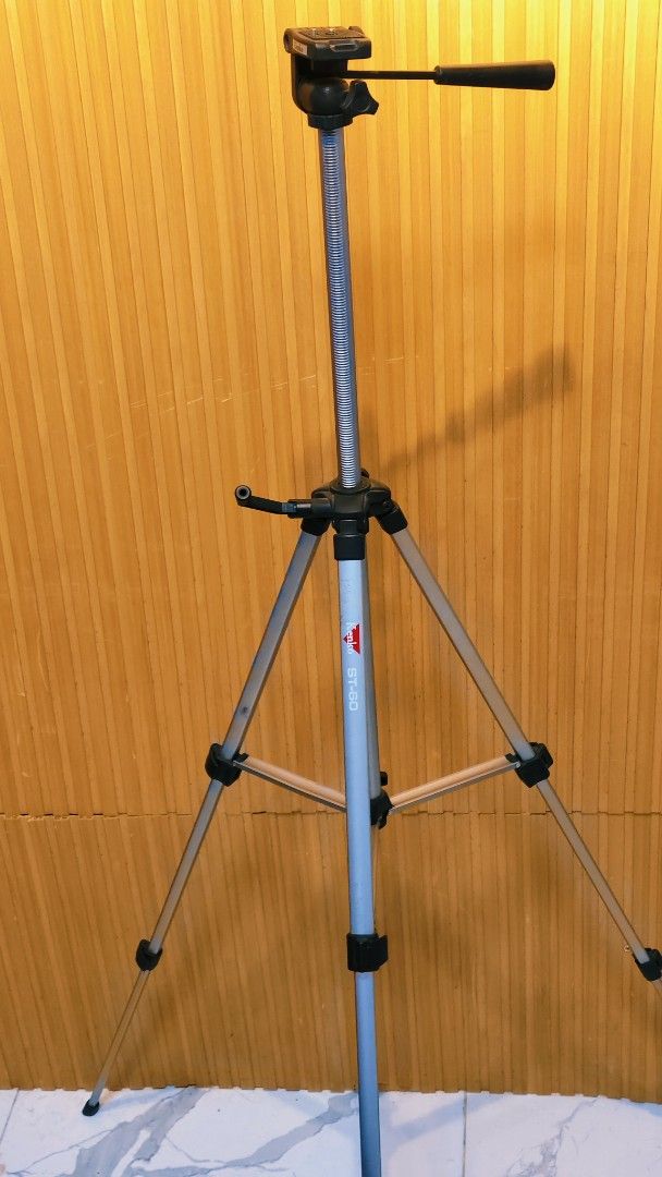 Kenko ST-60 Camera Tripod (Category: Tripods & Monopods) located in Bulacan. Submitted by babz30261 (Listing ID 1466166631, Image 3). Description: - Brand/Model: Kenko ST-60 Tripod - Build: Sturdy silver aluminum - Height Adjustment: Easy central crank handle - Head: Includes smooth pan head with control handle - Legs: Three-section with secure plastic flip locks - Condition: Fully functional; shows minor scuffs and dust from previous use - Best 