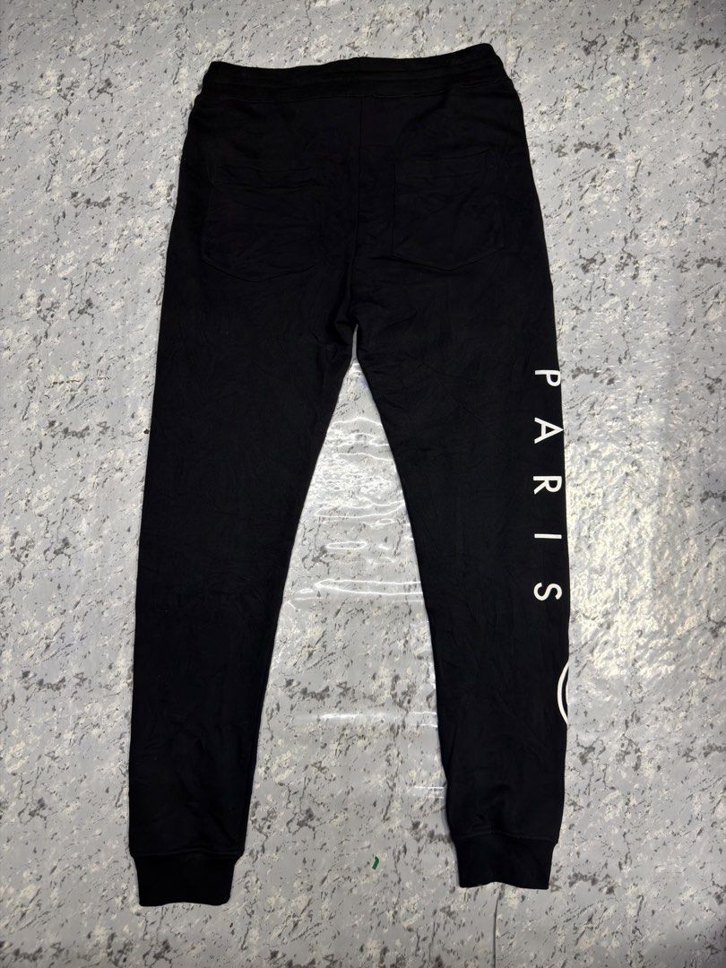 Kenzo Paris Black Joggers Sweatpants (Category: Joggers) located in Manila. Submitted by raven236 (Listing ID 1466195840, Image 2). Description: - Brand: Kenzo - Color: Black with large white logo branding on the right leg - Detail: Vertical PARIS lettering printed on the back right leg - Fit & Comfort: Drawstring elastic waist, ribbed ankle cuffs, and soft fleece lining inside - Pockets: Includes two back pockets - Style: Premium streetwear, com