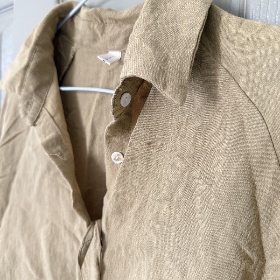 Khaki beige cropped button-down shirt blouse long sleeves (Category: Longsleeves) located in Angeles City. Submitted by elliemnopqrstuv (Listing ID 1466206713, Image 3). Description: - Color: Khaki beige - Style: Cropped button-down shirt with a loose, relaxed fit - Details: Collared neckline, white front buttons, long sleeves with gathered cuffs, and a tie string hem - Fabric: Soft, textured material - Styling: Great to pair with high-waisted je