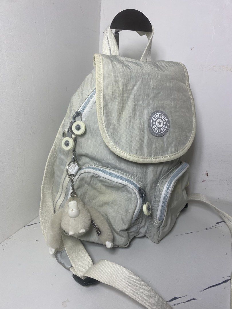 Kipling live.light Backpack White Grey (Category: Backpacks) located in Manila. Submitted by onfleekapparelph (Listing ID 1466168781, Image 2). Description: - Brand: Kipling - Color: Light Grey and White - Closure: Flap with magnetic snap - Pockets: Dual front zip pockets + inner zip pocket - Interior: Stylish black and white striped lining - Straps: Adjustable striped straps with top carry handle - Inclusion: Signature fuzzy monkey keychain - Co