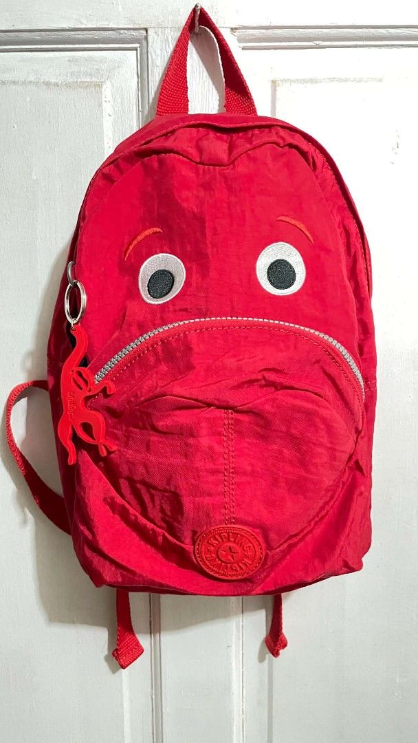 Kipling Red Monster Googly Eyes Backpack (Category: Backpacks) located in Manila. Submitted by xtinamendo00659 (Listing ID 1466287442, Image 1). Description: - Brand: Kipling mini backpack - Color: Bright red - Design: Quirky monster eyes and mouth zippered pocket - Material: Clean crinkle nylon fabric - Inclusion: Signature matching red monkey keychain charm - Hardware & Straps: Adjustable shoulder straps with black plastic hardware - Condition: