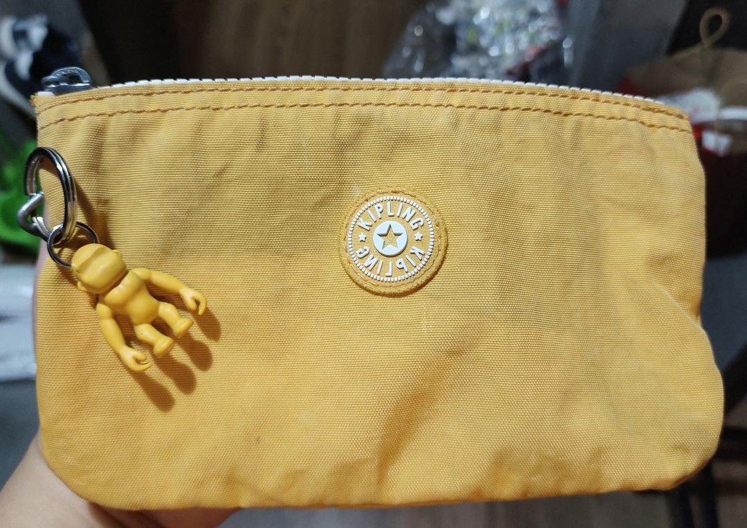 Kipling Yellow Pouch with Monkey Keychain (Category: Purses & Pouches) located in Calamba. Submitted by callcay (Listing ID 1466243441, Image 1). Description: - Authentic Kipling zipper pouch in a cheerful bright yellow shade - Made of durable and signature crinkled nylon material -with minimal flaw and ink stain - Features the iconic round Kipling logo patch on the front - Comes with an adorable matching yellow rubber monkey keychain - Secure to