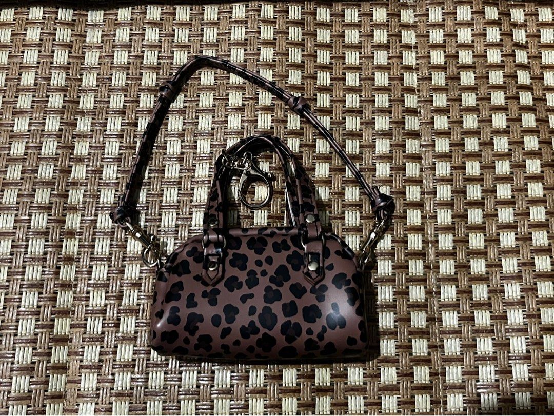 Leopard Print Micro Handbag With Strap and Keychain (Category: Purses & Pouches) located in Manila. Submitted by belledeclutters (Listing ID 1466245337, Image 1). Description: - Trendy mini leopard print handbag in brown and black - Palm-sized design: acts as a fun statement piece or bag charm - Features short grab handles and a long matching crossbody strap - Elegant gold-tone hardware throughout - Extra ring clasp attached to the front handle.