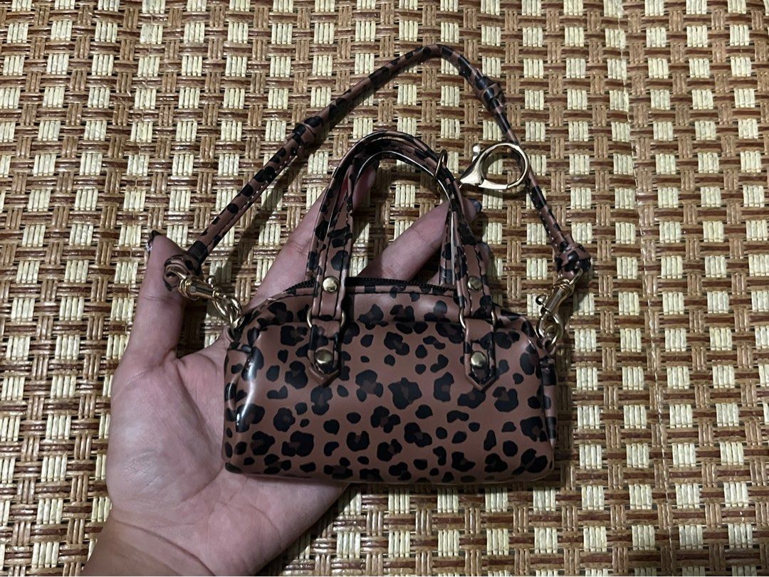 Leopard Print Micro Handbag With Strap and Keychain (Category: Purses & Pouches) located in Manila. Submitted by belledeclutters (Listing ID 1466245337, Image 3). Description: - Trendy mini leopard print handbag in brown and black - Palm-sized design: acts as a fun statement piece or bag charm - Features short grab handles and a long matching crossbody strap - Elegant gold-tone hardware throughout - Extra ring clasp attached to the front handle.