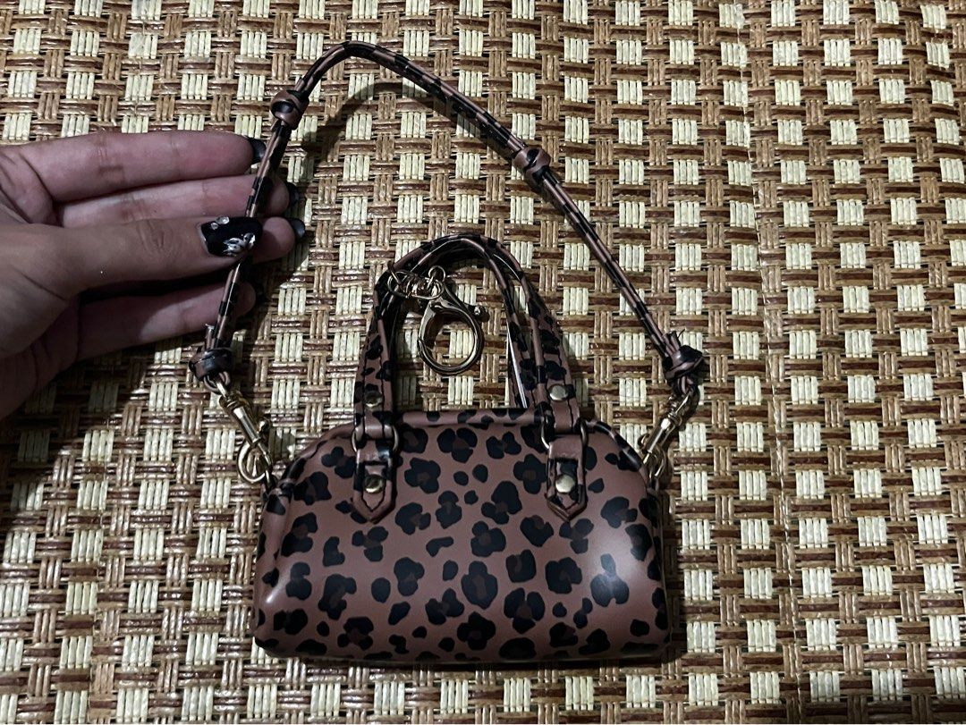 Leopard Print Micro Handbag With Strap and Keychain (Category: Purses & Pouches) located in Manila. Submitted by belledeclutters (Listing ID 1466245337, Image 2). Description: - Trendy mini leopard print handbag in brown and black - Palm-sized design: acts as a fun statement piece or bag charm - Features short grab handles and a long matching crossbody strap - Elegant gold-tone hardware throughout - Extra ring clasp attached to the front handle.