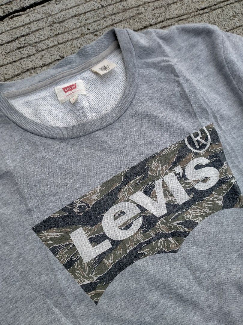 Levi's Grey Camo Box Logo Sweatshirt Size S (Category: Hoodies) located in Davao. Submitted by ervinpolino09 (Listing ID 1466269557, Image 2). Description: - Brand: Levi's - Color: Grey - Size: Small - Design: Camo print box logo with white Levi's lettering - Features: Long sleeves, ribbed cuffs/hem, soft interior fleece lining - Fit: Standard fit - Condition: Great casual piece for cooler weather.