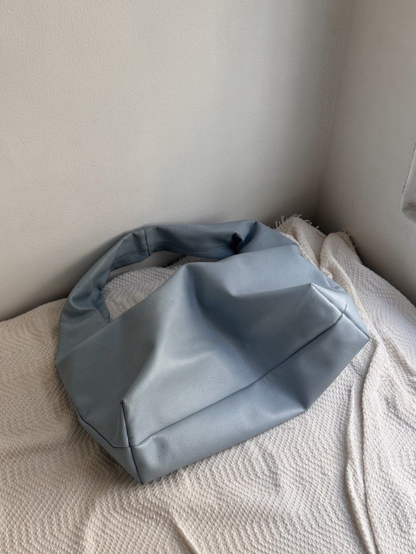 Light blue slouchy shoulder bag with zip (Category: Shoulder Bags) located in Rizal. Submitted by _shinnnb (Listing ID 1466177478, Image 2). Description: - Color: Muted blue - Material: Soft faux leather - Design: Slouchy crescent shape with a wide, twisted strap and structured base - Closure: Smooth top zip - Storage: Roomy interior for daily essentials - Style: Minimalist and casual.