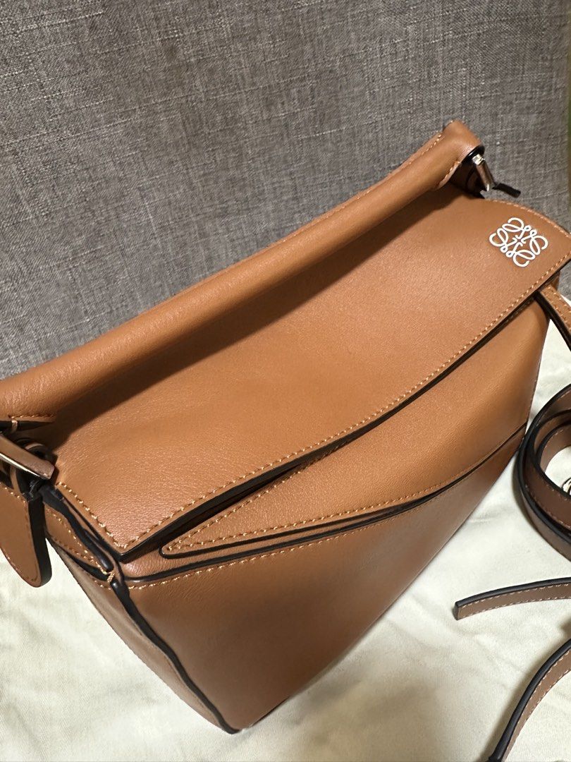 Loewe Puzzle Bag Tan (Category: Luxury Bags & Wallets) located in Manila. Submitted by jmsluxe2026 (Listing ID 1466199344, Image 3). Description: - Authentic Loewe Puzzle bag in timeless tan calfskin - Iconic geometric paneling with clean contrast stitching and black edge glazing - Versatile design: wear as a top handle, shoulder bag, or crossbody - Includes removable, adjustable shoulder strap with silver-toned hardware - Debossed Loewe anagram 