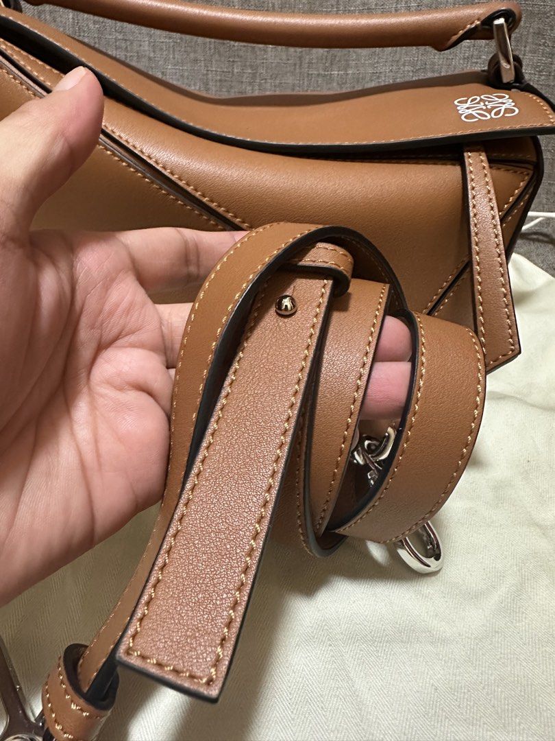 Loewe Puzzle Bag Tan (Category: Luxury Bags & Wallets) located in Manila. Submitted by jmsluxe2026 (Listing ID 1466199344, Image 2). Description: - Authentic Loewe Puzzle bag in timeless tan calfskin - Iconic geometric paneling with clean contrast stitching and black edge glazing - Versatile design: wear as a top handle, shoulder bag, or crossbody - Includes removable, adjustable shoulder strap with silver-toned hardware - Debossed Loewe anagram 