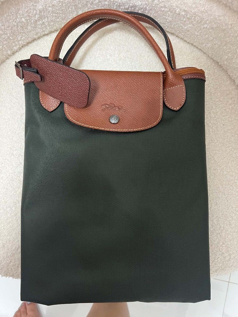 Longchamp Green Travel Bag (Category: Cross-body Bags) located in Paoay. Submitted by rvf1230 (Listing ID 1466230635, Image 3). Description: - Brand: Longchamp - Color: Deep green canvas with brown leather handles, corners, and strap - Condition: Clean inside and out - Interior: Black waterproof-style lining with multiple pockets - Closure: Full-length secure zip closure - Features: Includes a matching detachable shoulder strap with dark metal ha