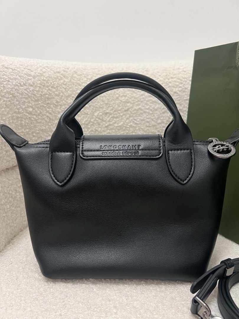 Longchamp Leather Small Crossbody Bag (Category: Luxury Bags & Wallets) located in Abulug. Submitted by jamiecammie (Listing ID 1466203155, Image 3). Description: Black leather Longchamp top handle bag. Silver tone hardware and embossed horse logo on the snap flap. Zip top closure with round pull stamped with Longchamp 1948. Removable shoulder strap included. Clean grain leather texture. Classic compact size for everyday essentials..