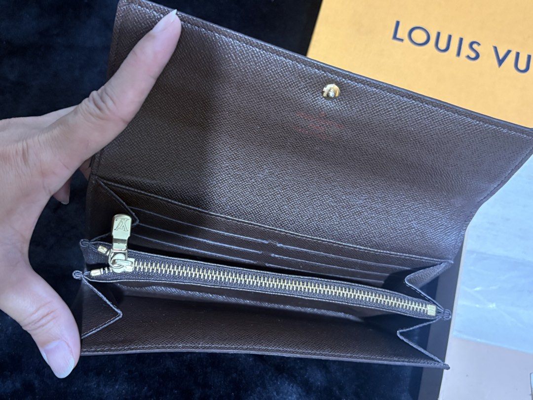 Louis Vuitton Damier Ebene Sarah Wallet (Category: Luxury Bags & Wallets) located in Manila. Submitted by nykji96 (Listing ID 1466199543, Image 2). Description: - Authentic Louis Vuitton Damier Ebene Canvas Wallet - Secure snap button front flap closure - Interior features multiple card slots, open compartments, and a zippered middle coin pocket - Elegant gold-tone hardware throughout - Includes original Louis Vuitton box and packaging materials.