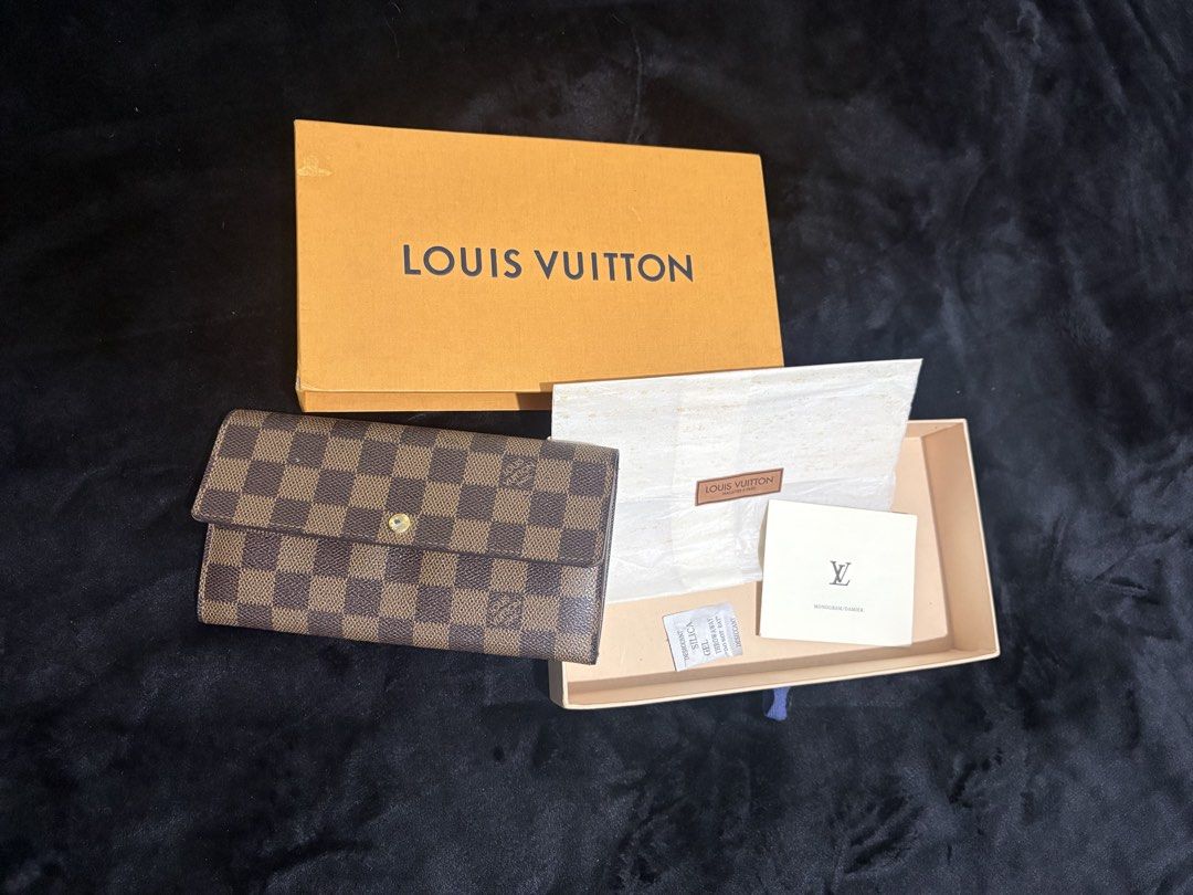 Louis Vuitton Damier Ebene Sarah Wallet (Category: Luxury Bags & Wallets) located in Manila. Submitted by nykji96 (Listing ID 1466199543, Image 1). Description: - Authentic Louis Vuitton Damier Ebene Canvas Wallet - Secure snap button front flap closure - Interior features multiple card slots, open compartments, and a zippered middle coin pocket - Elegant gold-tone hardware throughout - Includes original Louis Vuitton box and packaging materials.