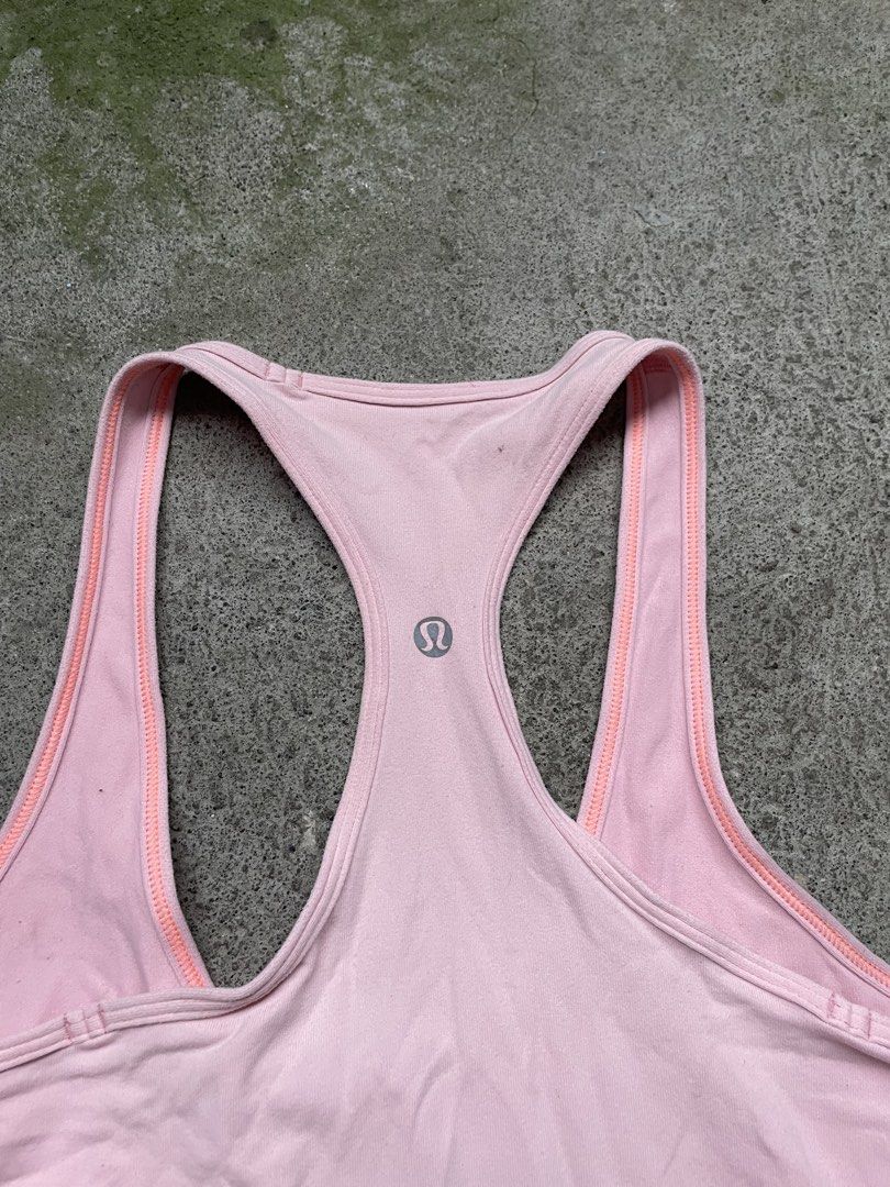 Lululemon Pink Tank Top (Category: Sleeveless) located in Siniloan. Submitted by rethr1ft (Listing ID 1466245068, Image 3). Description: - 27 length | 14 width - Brand: Lululemon - Color: Light pink with contrast orange piping - Style: Racerback, snug fit, long length - Details: Reflective silver omega logo on the back - Material: Stretchy, high-performance workout fabric - Condition: Excellent/Pre-loved (ready for yoga or runs).