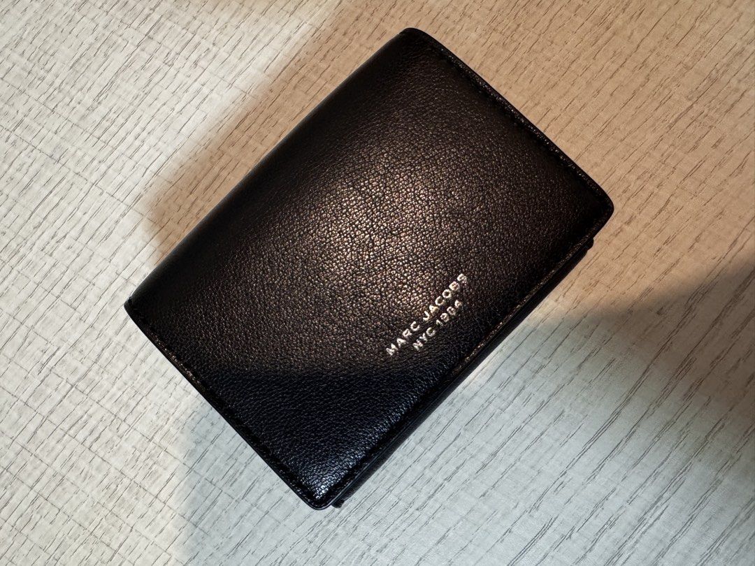Marc Jacobs Black Leather Trifold Wallet (Category: Luxury Bags & Wallets) located in Paranaque City. Submitted by lersprelovedclothes (Listing ID 1466255103, Image 2). Description: - Authentic Marc Jacobs NYC 1984 trifold wallet - Premium black grained leather with silver foil logo lettering - Secure snap button closure - Multiple card slots and slip compartments - Compact size, perfect for small bags and pockets - Clean interior with subtle bra