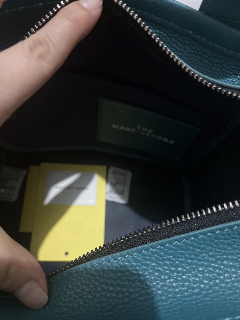 Authentic Marc Jacobs (Category: Luxury Bags & Wallets) located in Manila. Submitted by dominique_737 (Listing ID 1466311468, Image 2). Description: Marc Jacobs small leather tote bag in a vibrant teal color. Grainy leather texture, double top handles, detachable crossbody strap. Zipper top closure. Interior includes a slip pocket and branded fabric patch. Dust bag and tags included in the main compartment. Hardware stamped with Marc Jacobs lette