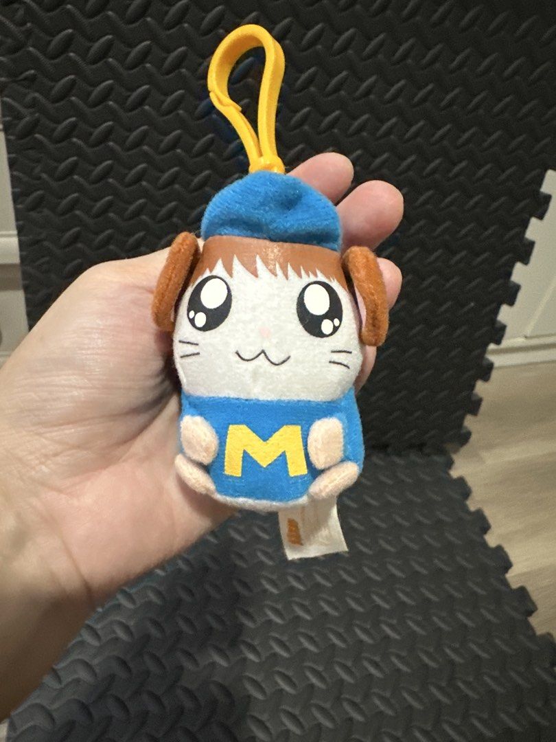 McDonald's Hamtaro Plush Keychain 2003 (Category: Character Goods) located in Cainta. Submitted by shopbyyna (Listing ID 1466264741, Image 1). Description: - Rare 2003 McDonald's Hamtaro plush keychain - Wears an adorable blue cap and blue shirt with the iconic yellow McDonald's M logo - Comes with a sturdy yellow plastic clip at the top for easy hanging - Features original white tag on the back with McDonald's copyright text and logo - Made with
