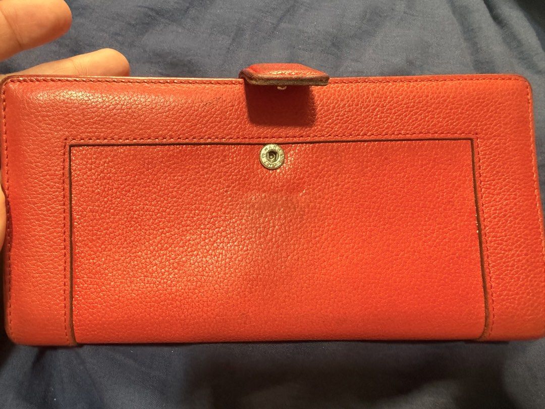 MCM Red Leather Long Wallet (Category: Luxury Bags & Wallets) located in Manila. Submitted by rrtolibas48132 (Listing ID 1466286275, Image 2). Description: - Brand: MCM München - Material: Red pebbled leather - Hardware: Gold-tone plaque with engraved serial number 12488 - Features: Clear ID window, multiple card slots, and exterior back snap pocket - Interior: Stamped with the official MCM logo - Condition: Normal wear on the leather grain and e
