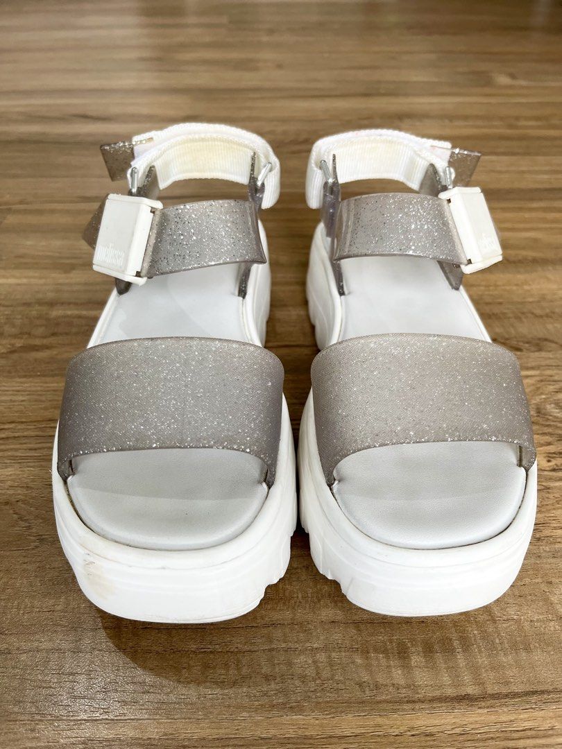 Melissa Glitter Platform Sandals White Silver Size 7 (Category: Flats & Sandals) located in Manila. Submitted by lorenasant37621 (Listing ID 1466207405, Image 2). Description: - Brand: Melissa - Style: Platform sandals with chunky lug sole and transparent glitter straps - Color: White and sparkly silver - Material: Vegan - Size: US 7 / EUR 38 / BRA 36 - Closure: Velcro back strap with buckle detail - Condition: Worn a few times, slight dirt marks
