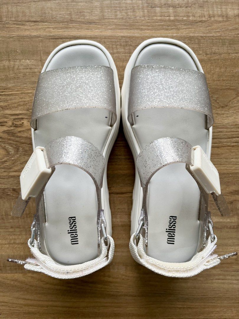 Melissa Glitter Platform Sandals White Silver Size 7 (Category: Flats & Sandals) located in Manila. Submitted by lorenasant37621 (Listing ID 1466207405, Image 1). Description: - Brand: Melissa - Style: Platform sandals with chunky lug sole and transparent glitter straps - Color: White and sparkly silver - Material: Vegan - Size: US 7 / EUR 38 / BRA 36 - Closure: Velcro back strap with buckle detail - Condition: Worn a few times, slight dirt marks
