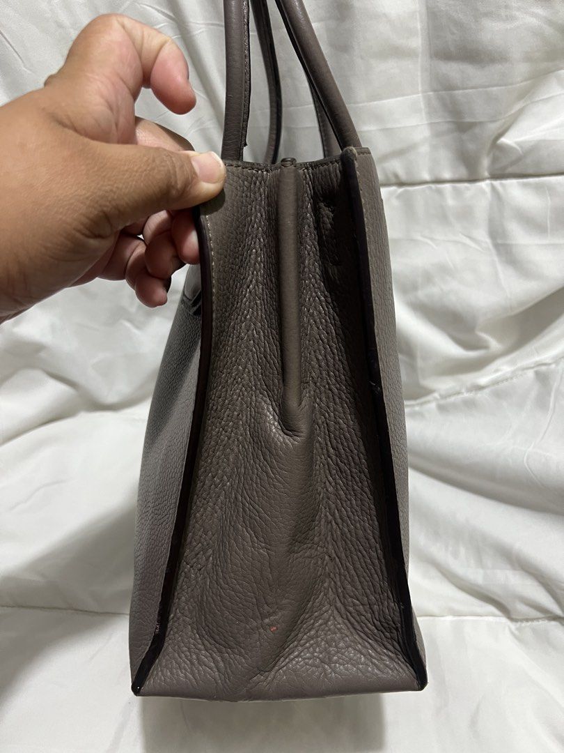 Michael Kors Mercer Medium Grey Leather Tote Bag (Category: Tote Bags) located in Pasig City. Submitted by madiesbags (Listing ID 1466328315, Image 2). Description: - Brand: Michael Kors - Material: Taupe grey pebble leather with silver hardware - Design: Structured base with metal feet and signature padlock charm - Interior: Fabric-lined with multiple compartments and a secure zippered pocket - Closure: Top zip closure for security - Condition: 