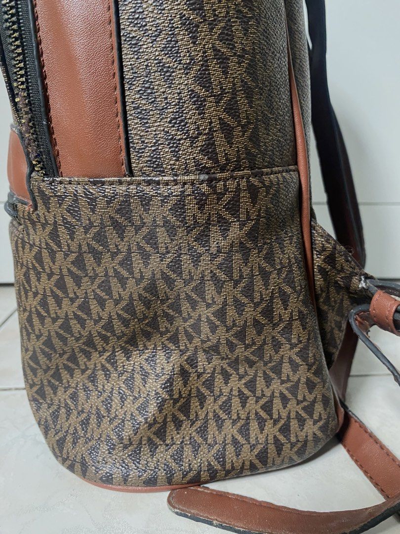 Michael Kors MK Monogram Brown Leather Backpack (Category: Backpacks) located in Marikina City. Submitted by makeitmorepretty (Listing ID 1466162697, Image 3). Description: Brown Michael Kors backpack featuring the iconic MK monogram pattern throughout. Accented with smooth brown leather trim and gold-tone hardware. Front zip pocket with Michael Kors lettering logo plaque. Top zip closure and adjustable shoulder straps. Roomy interior compartment