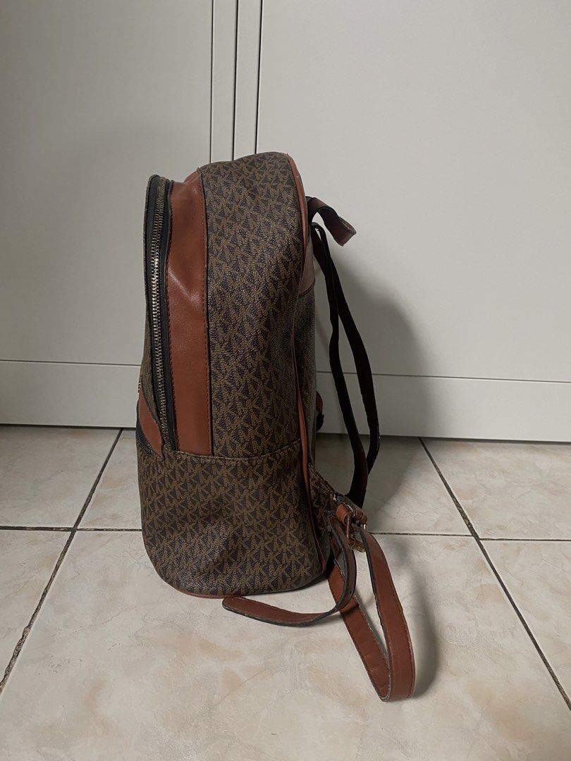 Michael Kors MK Monogram Brown Leather Backpack (Category: Backpacks) located in Marikina City. Submitted by makeitmorepretty (Listing ID 1466162697, Image 2). Description: Brown Michael Kors backpack featuring the iconic MK monogram pattern throughout. Accented with smooth brown leather trim and gold-tone hardware. Front zip pocket with Michael Kors lettering logo plaque. Top zip closure and adjustable shoulder straps. Roomy interior compartment