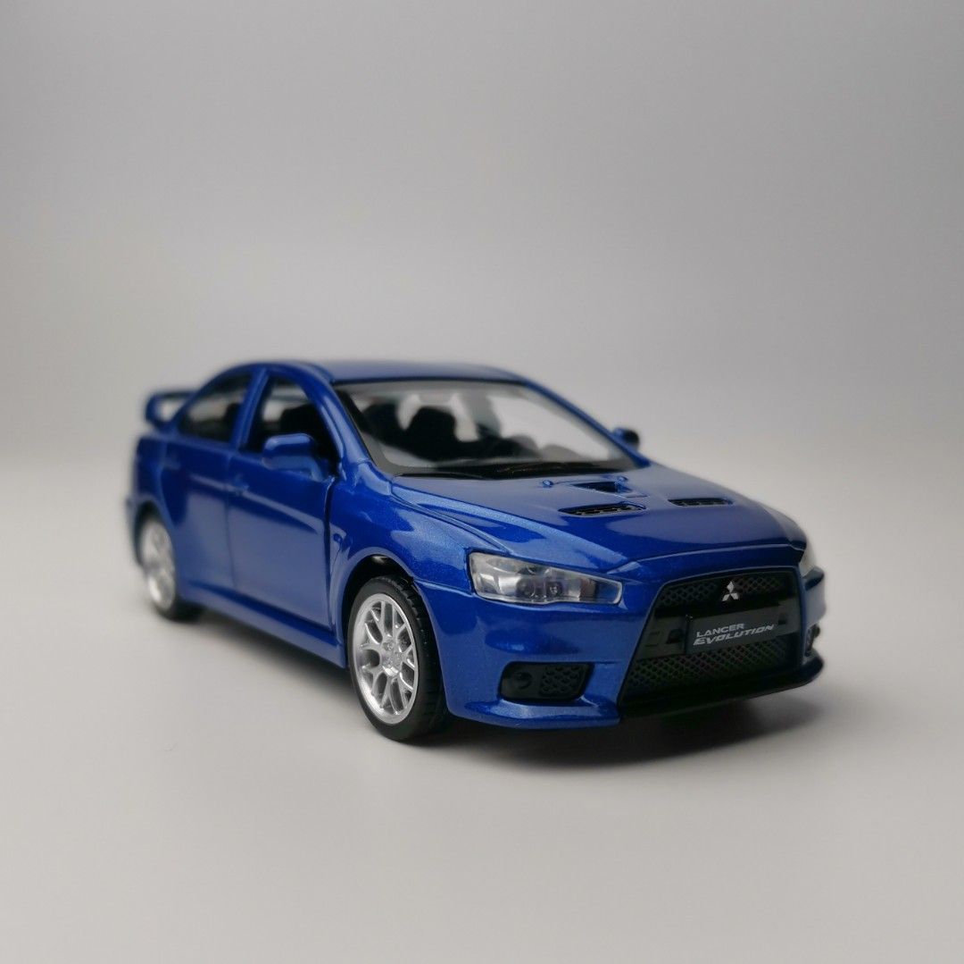 Mitsubishi Lancer Evolution X 1:41 Scale Diecast Model Car (Category: Vehicle & Diecast Models) located in Tanza. Submitted by alloytoys (Listing ID 1466258008, Image 2). Description: - Model: Mitsubishi Lancer Evolution X - Scale: 1:41 alloy diecast - Color: Blue - Features: Opening front doors, detailed interior, and rear spoiler - Wheels: Silver multi-spoke wheels - Packaging: Comes in original box.