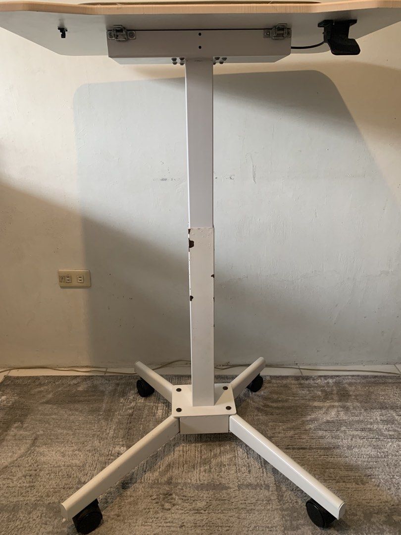 Mobile Height Adjustable Standing Desk Rolling Lectern (Tilting, 61cm x 80cm Table) (Category: Office Furniture & Fixtures) located in Las Pinas. Submitted by happy.u (Listing ID 1466243635, Image 3). Description: Location: Las Pinas MOP: GCash ITEM DETAILS Type: Rolling standing desk with hand-lever height adjustment, tilting table top Design: Light wood-grain top and heavy-duty four-prong white metal base Mobility: Equipped with 4 smooth-rollin