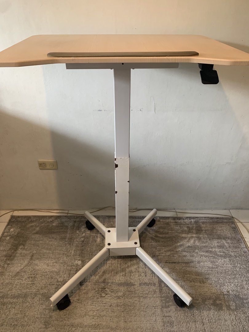 Mobile Height Adjustable Standing Desk Rolling Lectern (Tilting, 61cm x 80cm Table) (Category: Office Furniture & Fixtures) located in Las Pinas. Submitted by happy.u (Listing ID 1466243635, Image 2). Description: Location: Las Pinas MOP: GCash ITEM DETAILS Type: Rolling standing desk with hand-lever height adjustment, tilting table top Design: Light wood-grain top and heavy-duty four-prong white metal base Mobility: Equipped with 4 smooth-rollin