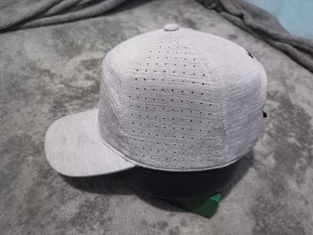 Nike 7 Panel Dri-Fit Gray Athletic Cap with Swoosh Logo (Category: Caps & Hats) located in Manila. Submitted by thecomftrift.co (Listing ID 1466324694, Image 3). Description: Gray Nike cap with a classic black embroidered Swoosh logo on the front and back. Features laser-perforated ventilation holes along the sides for airflow during workouts or runs. Adjustable hook-and-loop strap in the back for a custom fit. Textured heather-style fabric all o
