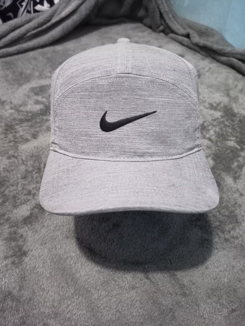 Nike 7 Panel Dri-Fit Gray Athletic Cap with Swoosh Logo (Category: Caps & Hats) located in Manila. Submitted by thecomftrift.co (Listing ID 1466324694, Image 1). Description: Gray Nike cap with a classic black embroidered Swoosh logo on the front and back. Features laser-perforated ventilation holes along the sides for airflow during workouts or runs. Adjustable hook-and-loop strap in the back for a custom fit. Textured heather-style fabric all o