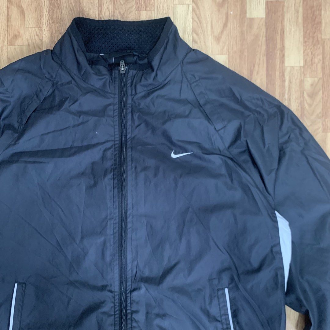 Nike Black Zip-Up Windbreaker Jacket (Category: Coats, Jackets and Outerwear) located in Cebu City. Submitted by zen.lasonking (Listing ID 1466228657, Image 2). Description: - Brand/Model: Nike Black Zip-Up Windbreaker - Size: Medium - Color: Black with white accent panels on both sides - Branding: White Swoosh logo on front left chest - Pockets: Two secure zippered side pockets with reflective piping detail - Lining: Breathable mesh lining insid