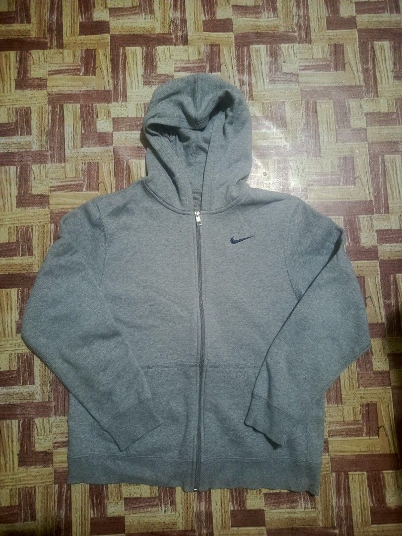 Nike Grey Zip-Up Hoodie (Category: Hoodies) located in Pasig City. Submitted by atmclick (Listing ID 1466290463, Image 1). Description: - Brand: Nike - Style: Full-zip athletic hoodie - Size: XL - 21x24.5 - Color: Grey with small blue embroidered Swoosh on chest - Material: Warm fleece lining inside - Features: Adjustable drawstring hood, front split kangaroo pockets, ribbed cuffs and hem - Condition: Excellent condition .
