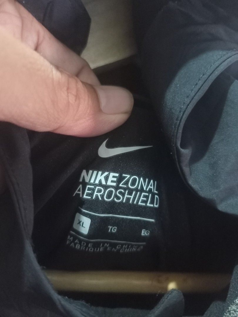 Nike Windbreaker Aeroshiel Jacket Black XL (Category: Coats, Jackets and Outerwear) located in Taguig. Submitted by mvdsh0p2022 (Listing ID 1466279725, Image 2). Description: Nike Zonal Aeroshield jacket in black. Men size XL. Full zip front with attached hood. Reflective swoosh logo on chest and lettering on sleeve. Vented back yoke for breathability. Lightweight weather-resistant fabric. Clean look, ready for outdoor runs or daily wear. N.i.k.e