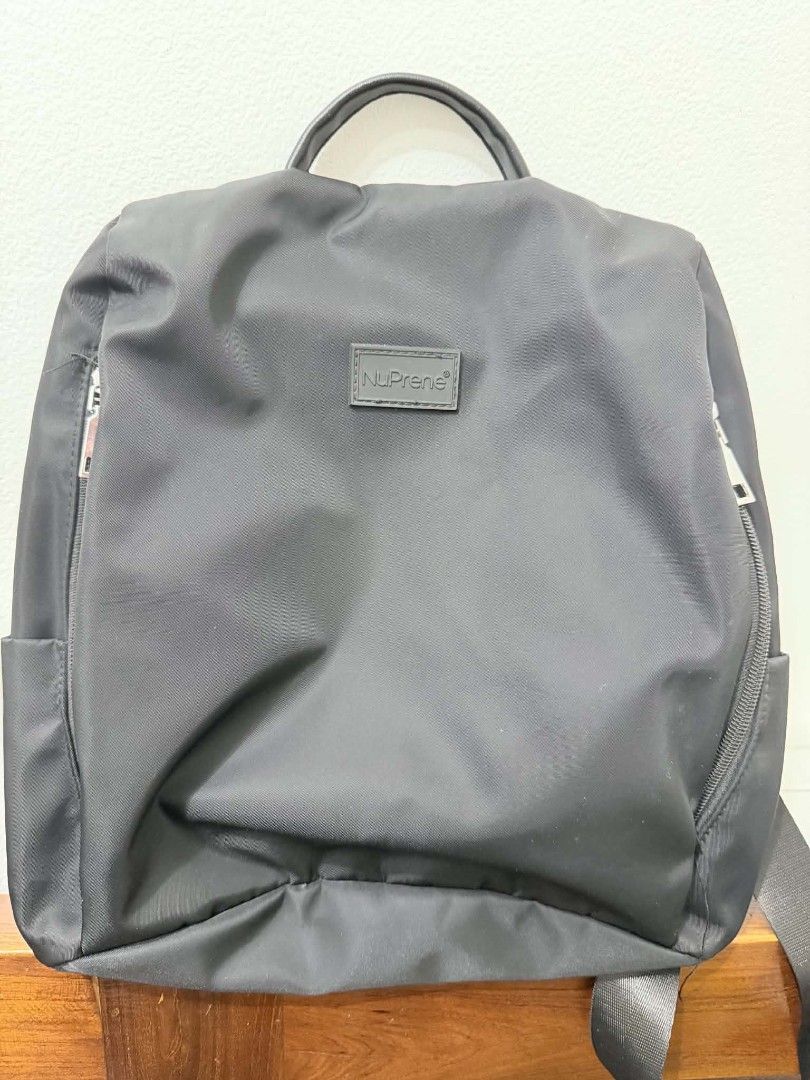 NuPrene Black Nylon Backpack (Category: Backpacks) located in Caloocan City. Submitted by jennraean (Listing ID 1466235563, Image 1). Description: - Brand: NuPrene - Color: Black - Material: Durable nylon - Design: Simple minimalist style with front logo patch - Features: Top handle, adjustable shoulder straps, and secure zipped compartments - Condition: Clean interior and 100% working smooth zippers - Ideal for: Daily commutes, school, or casual