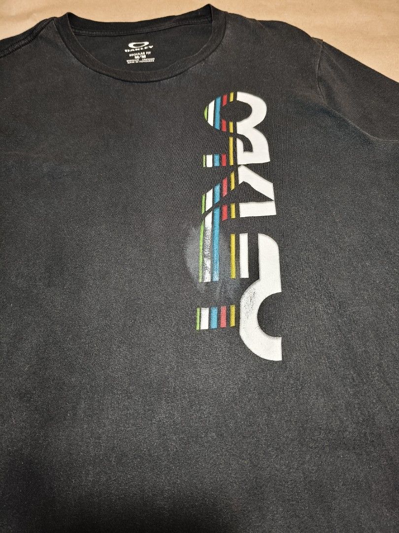 Oakley Black Regular Fit T-Shirt Size M (Category: Tshirts & Polo Shirts ) located in Manila. Submitted by thriftclothin (Listing ID 1466204607, Image 2). Description: - Brand: Oakley - Style: Short-sleeve crew neck t-shirt - Size: Medium (Regular fit) - Design: Vertical multi-color graphic print on front chest - Material: Cotton with normal wash fade - Condition: Pre-loved, casual wear ready - Trusted seller: Fast shipping across the Philippines