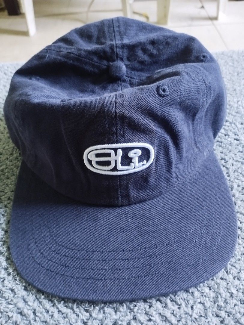 OLI Navy Blue Cotton Cap (Category: Caps & Hats) located in Manila. Submitted by happycaps (Listing ID 1466176643, Image 1). Description: - Brand: OLI (Designed in Australia) - Color: Dark blue with embroidered white logo patch - Material: 100% cotton - Fit: Adjustable strap in the back with a metal clasp - Condition: Clean fabric, minimal wear.