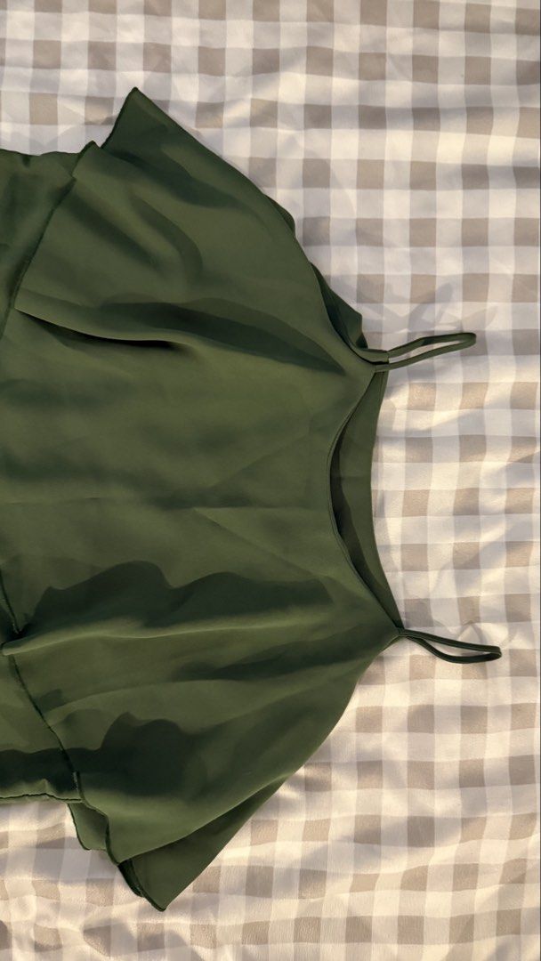 Olive green spaghetti strap ruffle overlay camisole top (Category: Sleeveless) located in Muntinlupa City. Submitted by addielejano (Listing ID 1466267084, Image 3). Description: - Color: Dark olive green - Style: Camisole with thin spaghetti straps - Design: Layered ruffle overlay draping over the shoulders - Fabric: Lightweight and breathable - Condition: Clean, excellent, ready to wear Fits S-M.