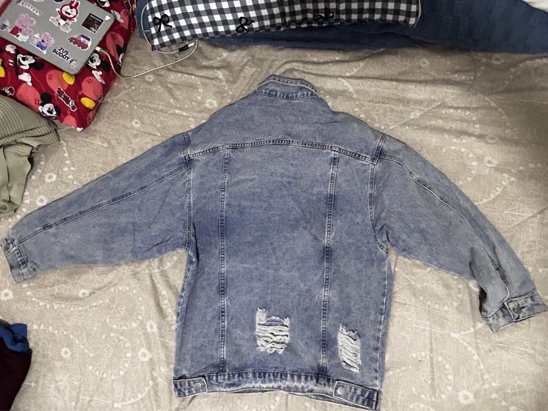 Oversized Distressed Blue Denim Jacket with Rips (Category: Coats, Jackets and Outerwear) located in Caloocan City. Submitted by hansev (Listing ID 1466289180, Image 3). Description: - Style: Oversized fit denim jacket - Color: Light wash blue - Design: Button-up front, classic collar, and button cuffs - Pockets: Functional chest and lower side pockets - Details: Trendy distressed rips on the chest, sleeves, and lower back - Versatility: Easy to 