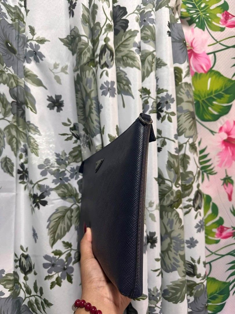 P R A D A (Category: Luxury Bags & Wallets) located in Tambulig. Submitted by cmscloset_ph (Listing ID 1466290216, Image 2). Description: PRADA Saffiano leather clutch in navy blue - Sleek structured shape with silver-tone hardware - Classic triangular metal logo plate on the front - Secure zip top closure with fully lined interior - Medium size: ideal for essentials or as a tote insert.