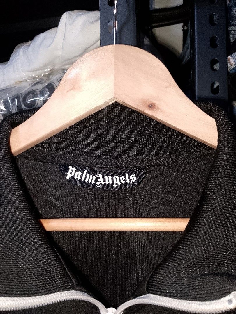 Palm Angels Black Track Jacket Size M (Category: Coats, Jackets and Outerwear) located in Manila. Submitted by mjthrifted_second (Listing ID 1466207418, Image 2). Description: - Brand: Palm Angels - Style: Black track jacket with white side stripes and front zipper - Details: White Palm Angels logo on left chest, two side zip pockets - Fit/Size: Size M -Dimes: 23/28 - Material: 100% polyester - Condition: Clean, excellent, and ready to wear.