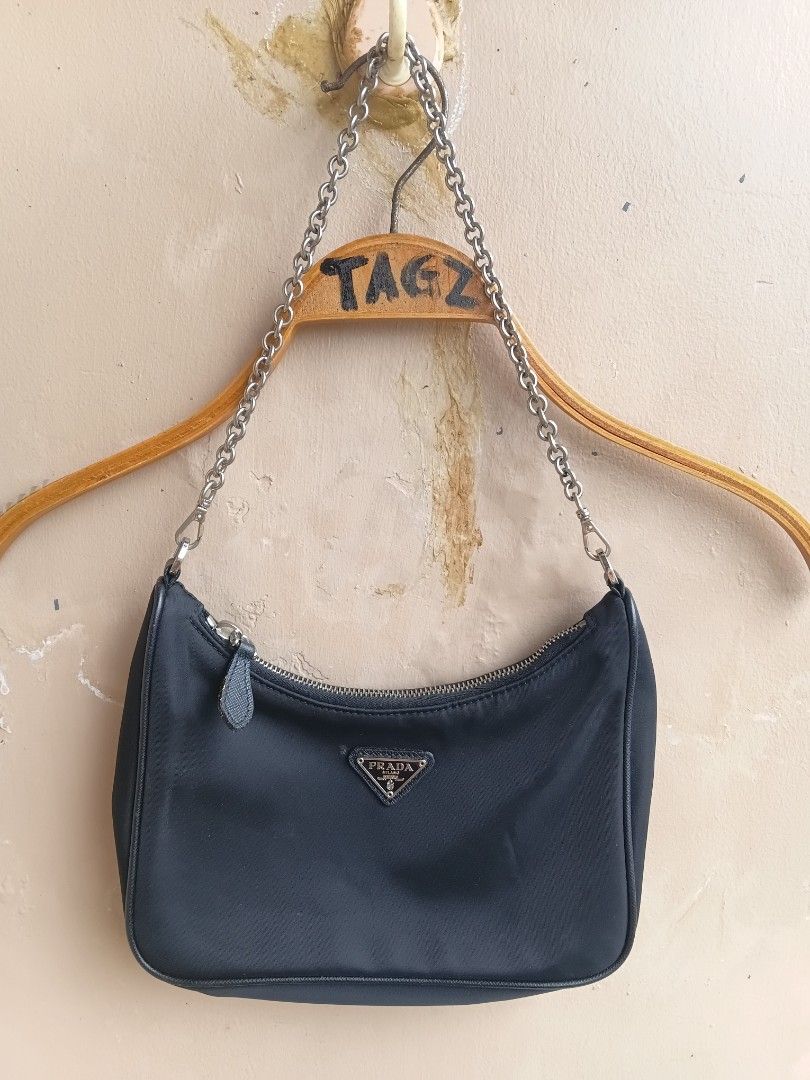 Prada Black Nylon Mini Shoulder Bag (Category: Luxury Bags & Wallets) located in Manila. Submitted by grandflower-547aee (Listing ID 1466222610, Image 1). Description: - Brand: Prada - Material: Classic black nylon - Hardware: Silver-tone chain strap and zipper closure - Details: Iconic metal triangle logo plaque on the front - Interior: Prada logo lining with 'Made in Italy' tag - Condition: Vintage, clean exterior and interior.
