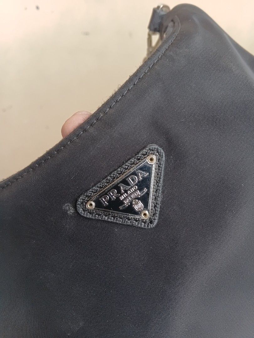 Prada Black Nylon Mini Shoulder Bag (Category: Luxury Bags & Wallets) located in Manila. Submitted by grandflower-547aee (Listing ID 1466222610, Image 3). Description: - Brand: Prada - Material: Classic black nylon - Hardware: Silver-tone chain strap and zipper closure - Details: Iconic metal triangle logo plaque on the front - Interior: Prada logo lining with 'Made in Italy' tag - Condition: Vintage, clean exterior and interior.