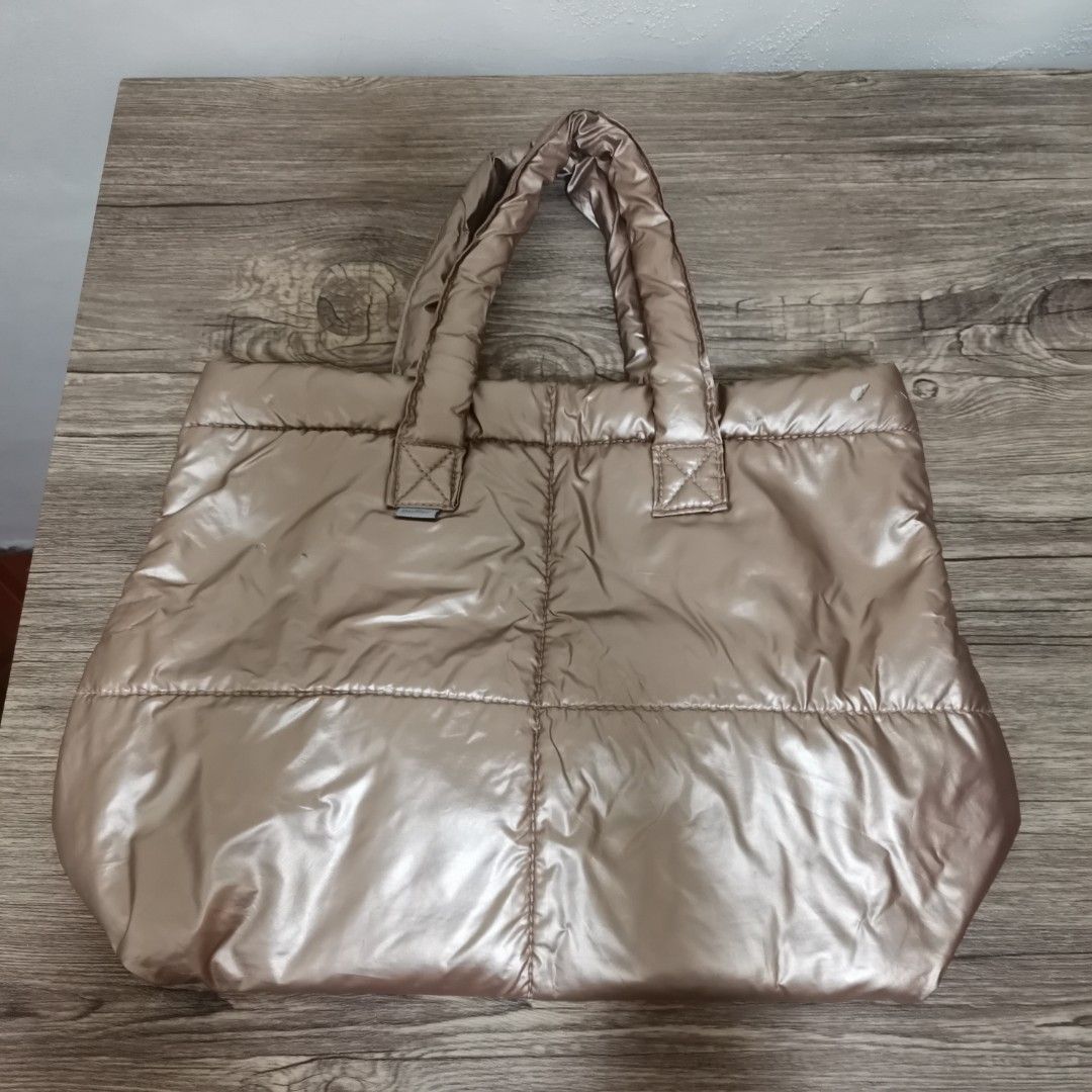 Puffer Tote Bag (Category: Tote Bags) located in Bacoor. Submitted by bloomingpetals (Listing ID 1466200734, Image 1). Description: Surplus Puffer Tote Bag ₱150 FIXED PRICE • Beige/taupe color • Size: 33 × 25 × 15 cm • Material: Nylon Metallic • Puffer/padded design • Magnetic closure • With 1 inner pocket • Lightweight and spacious • Can be carried by hand or on the shoulder • Suitable for everyday/casual use Condition: Well-used preloved ⚠️ Ple