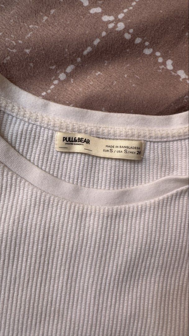 Pull&Bear White Ribbed Crop Top Size S (Category: Shirts) located in Quezon City. Submitted by meezck (Listing ID 1466188026, Image 1). Description: - Brand: Pull&Bear - Style: Ribbed top with scoop neckline and short sleeves - Color: White - Size: S (Made in Bangladesh) - Material: Soft, textured fabric with stretch - Condition: Clean and ready to wear - Versatile: Easy to pair with high-waisted jeans or skirts.