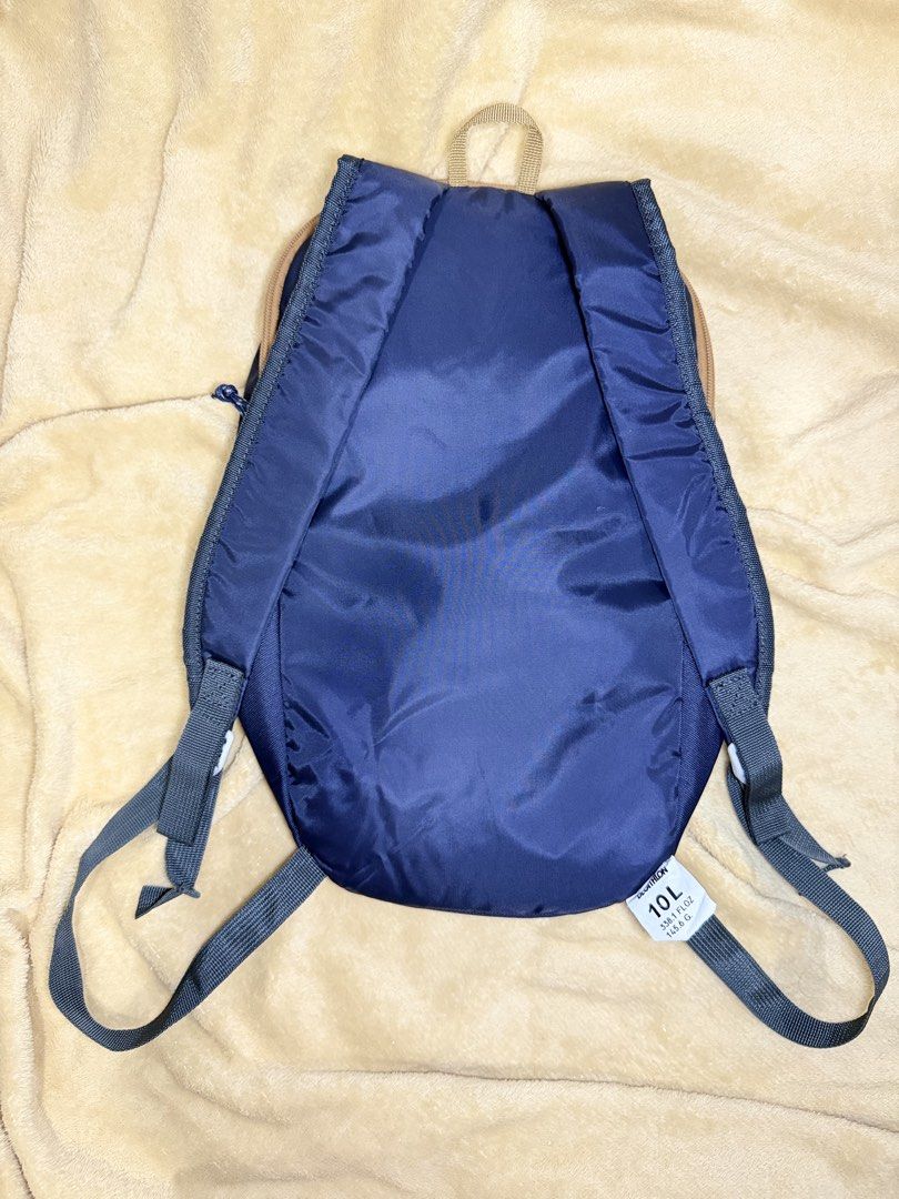 Quechua Decathlon 10L Navy Blue Backpack (Category: Backpacks) located in Manila. Submitted by maligayangthrift (Listing ID 1466259600, Image 2). Description: - Brand: Quechua - Color: Deep navy blue with stylish brown zipper tape and top handle - Capacity: 10L (Compact and lightweight) - Compartments: Main compartment with a zippered front pocket for small items - Comfort: Adjustable padded shoulder straps.